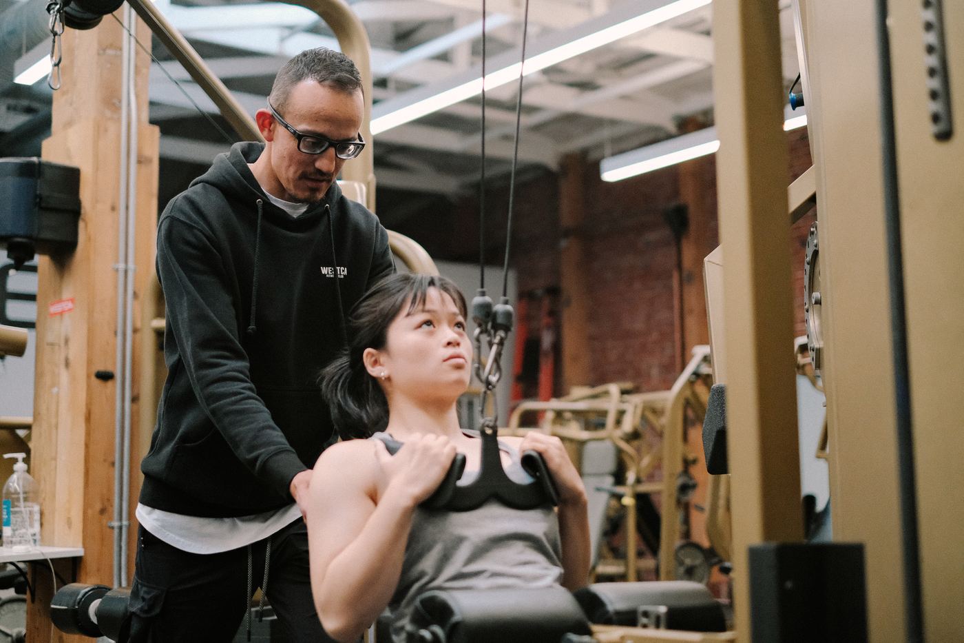 A WESTCA coach guiding a client on the lat pulldown