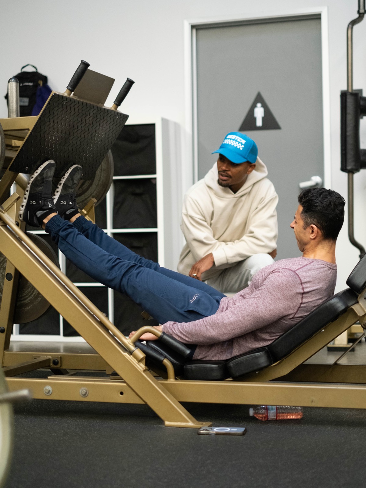 A coach and member on the leg press